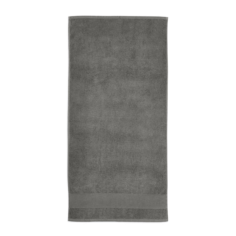 A grey cotton towel, featuring a textured finish, with a subtle branding logo at one end. Made in Portugal.