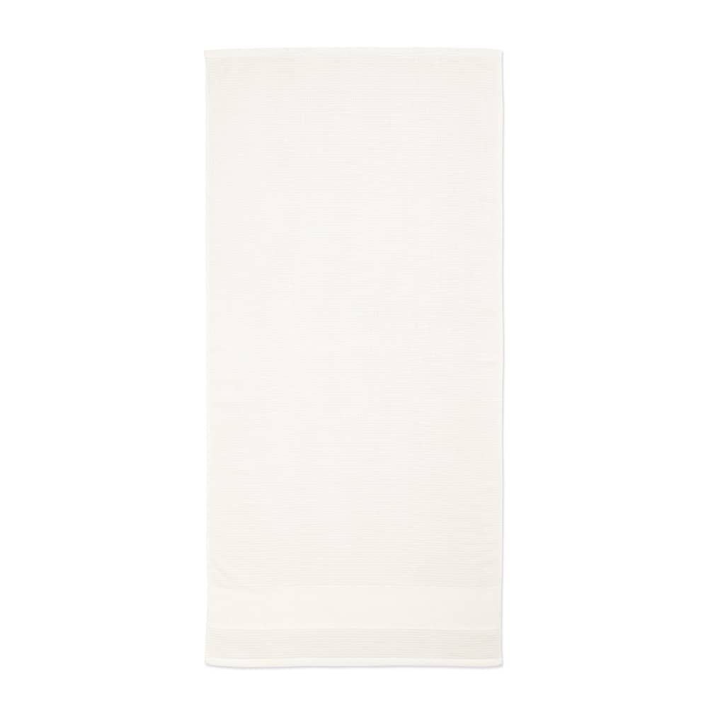 A white towel, made from cotton, featuring a soft texture and a logo on the side.