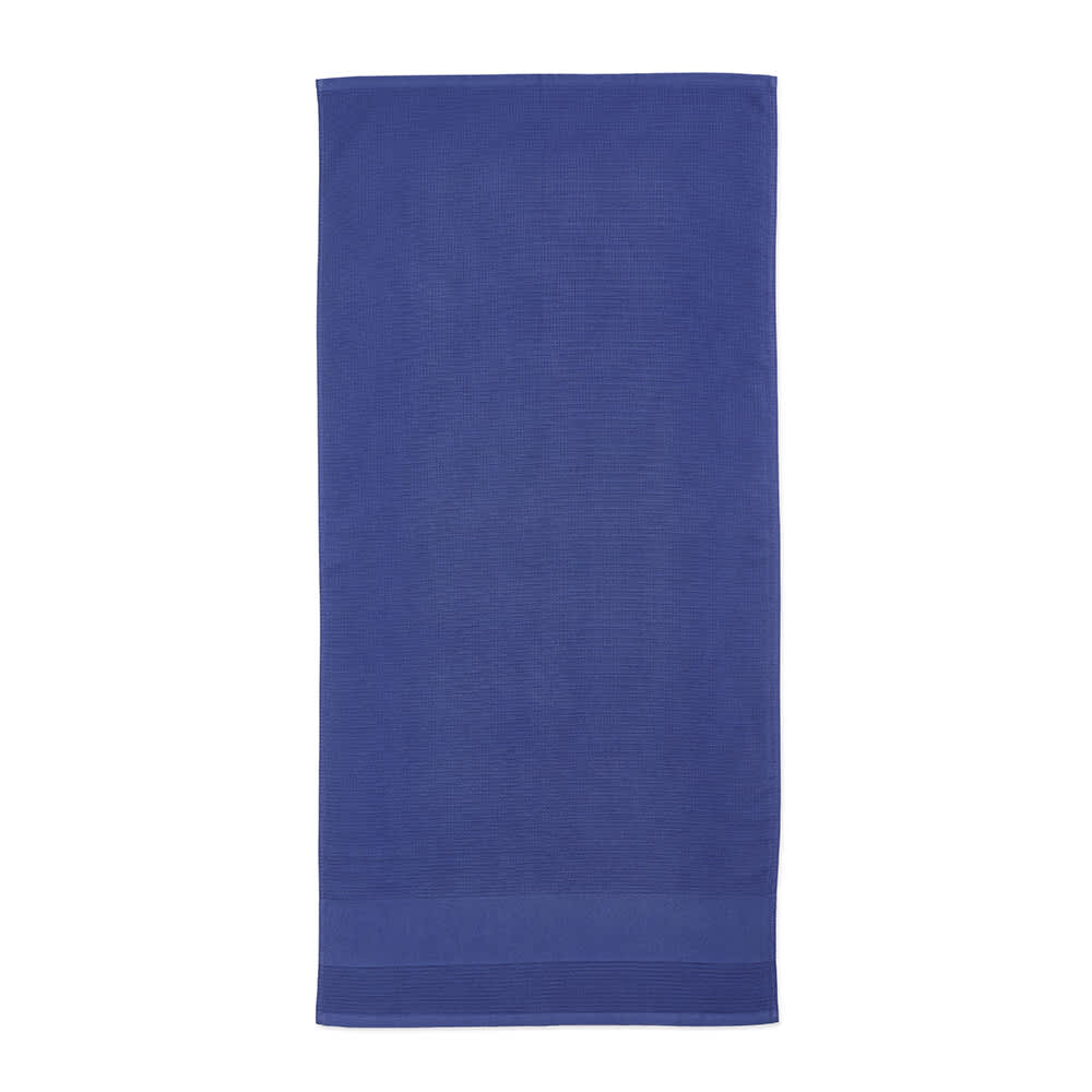A purple cotton towel with a textured pattern, featuring a logo or branding at the bottom.