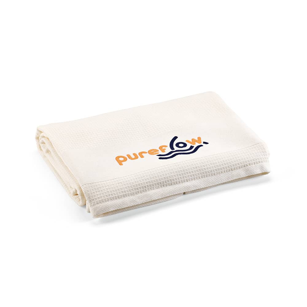 A folded cream towel made of cotton, featuring a logo in orange and blue.