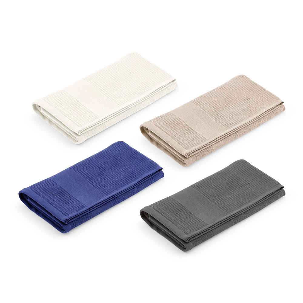 Four cotton towels in cream, beige, navy blue, and grey, folded neatly with a logo on one.