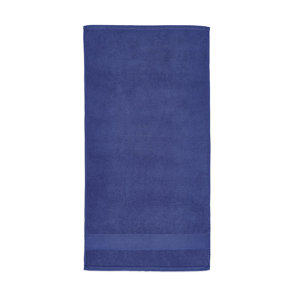 A deep blue towel made of cotton, featuring a smooth texture and a subtle stripe at the bottom. It has a logo.