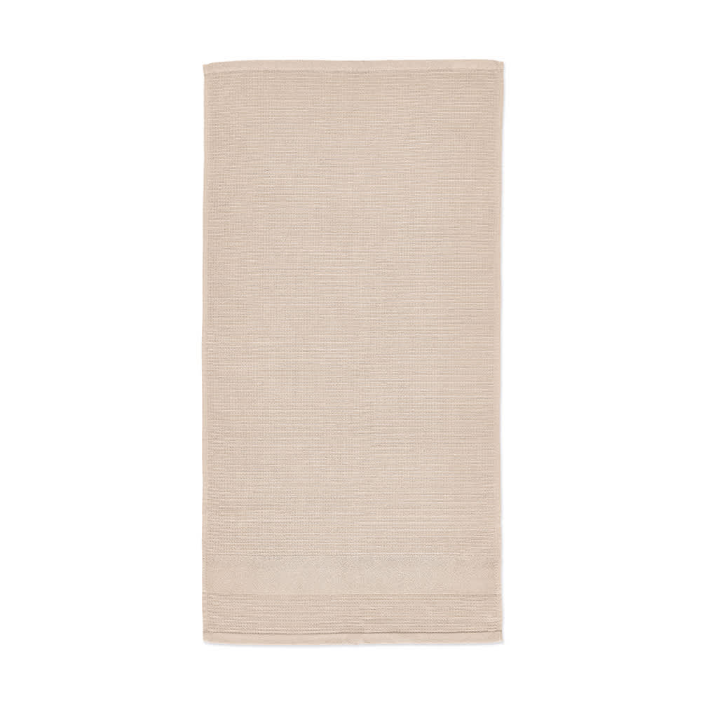 A towel in a soft beige colour with a textured stripe pattern. It has a branding logo present.