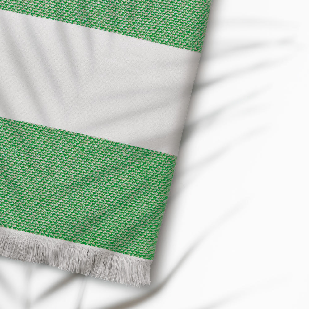 A green and white striped towel with fringing, made from cotton and featuring a logo.