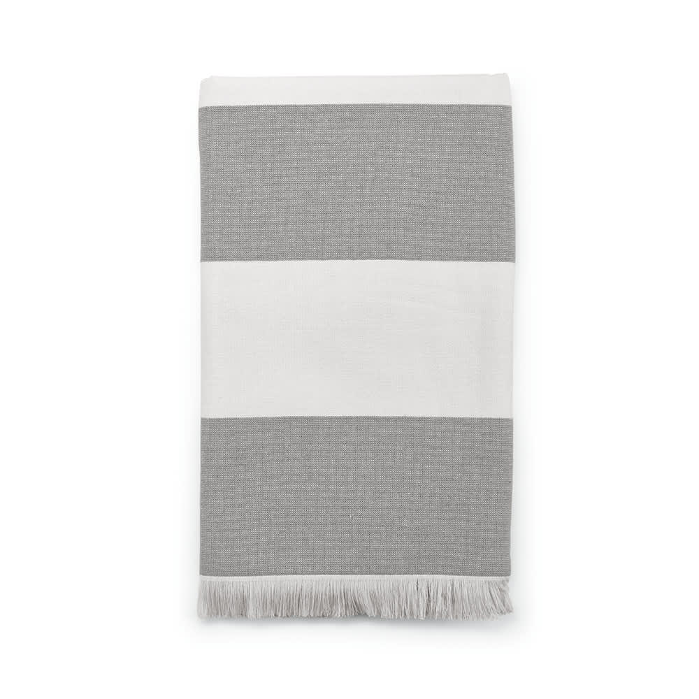 A grey and white striped towel featuring fringed edges, made from 350gsm cotton in Portugal. It has a logo.