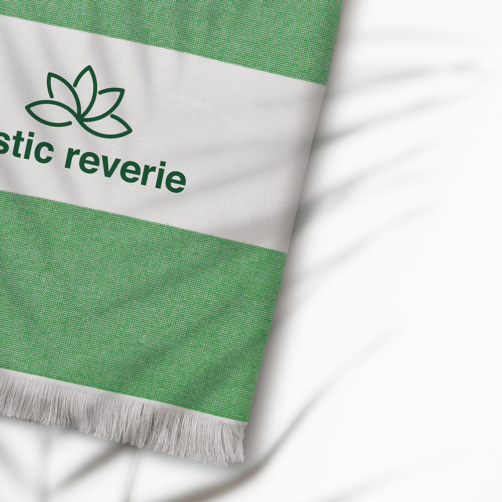 A green and white striped towel with a logo, featuring a fringed edge and a soft texture.