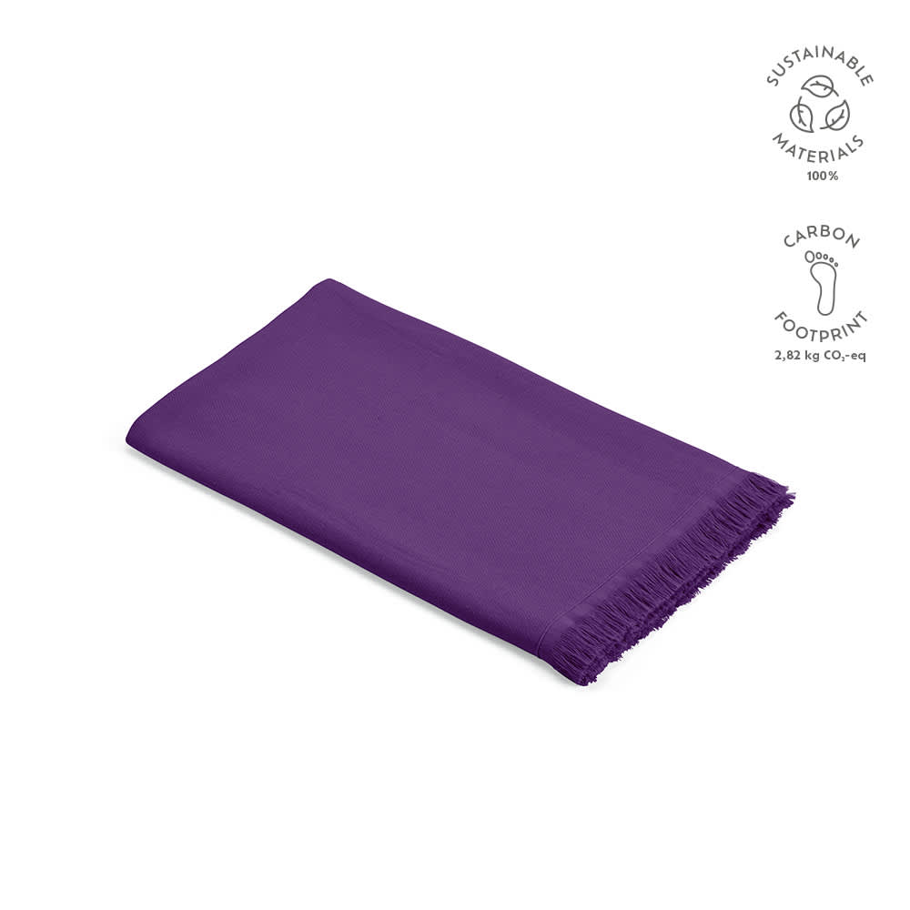 A purple towel made of 100% sustainable cotton with fringed edges, featuring a branding logo.