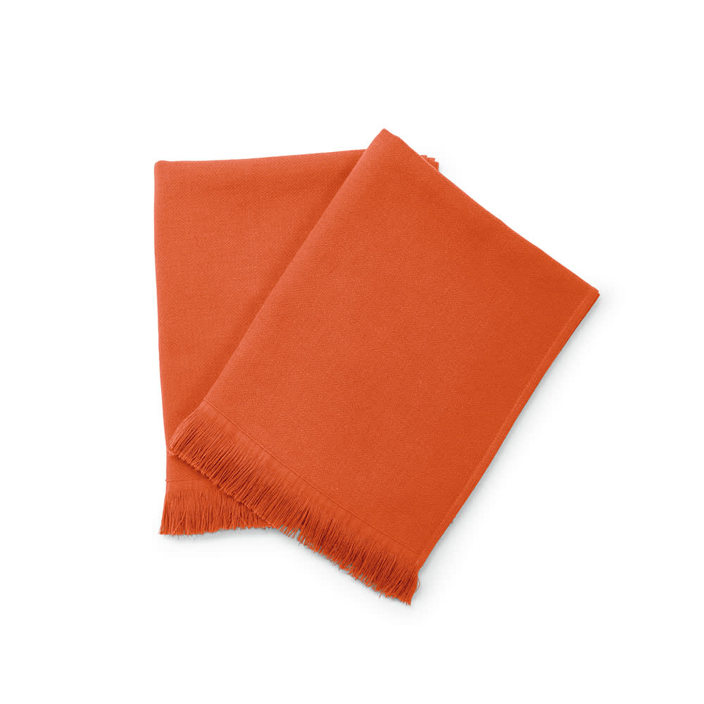 An orange towel made of cotton, featuring fringed edges. It has a logo on it.