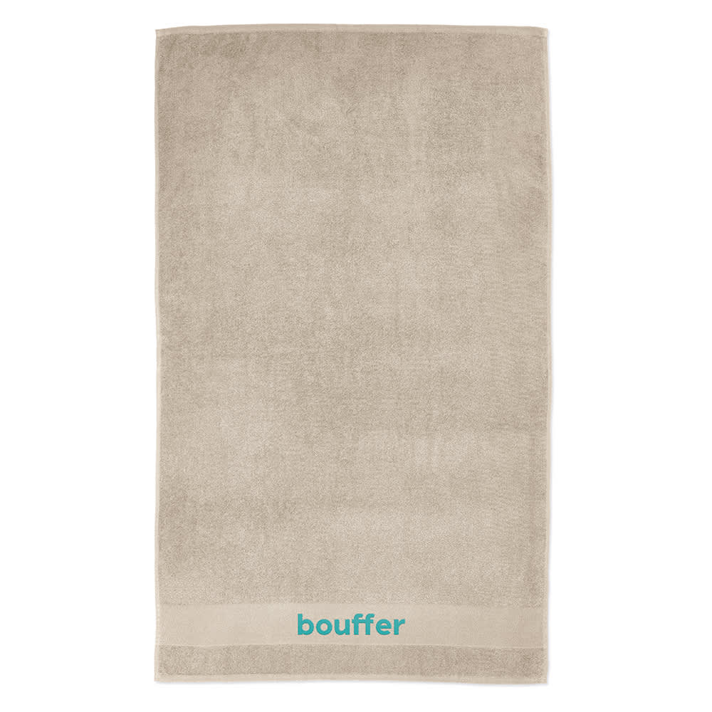 A large, beige towel made from cotton with a logo at the bottom. Soft texture, suitable for various uses.
