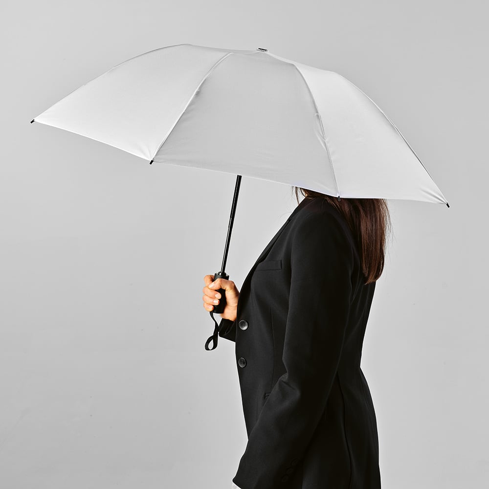 A white, foldable umbrella is held by a person in formal attire against a grey background.