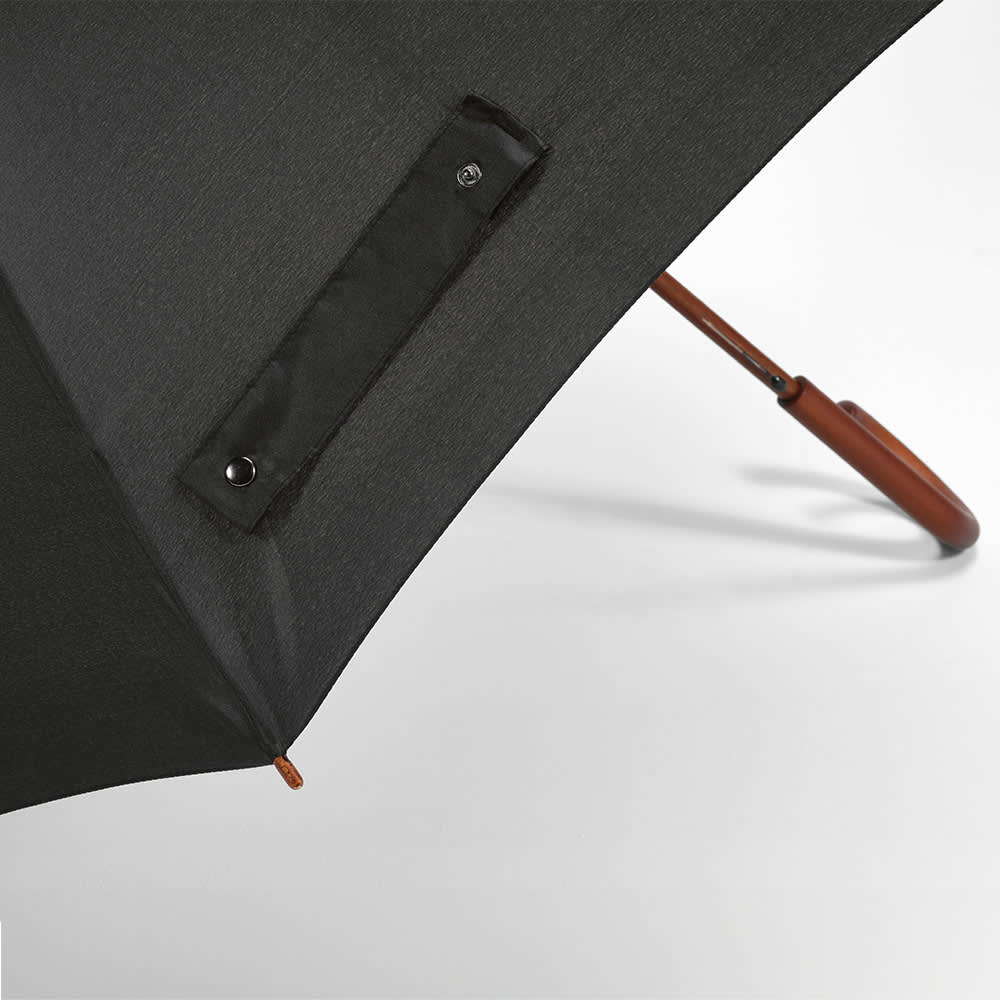A black umbrella with a brown handle and a logo patch on the fabric. It features a windproof design and automatic opening.