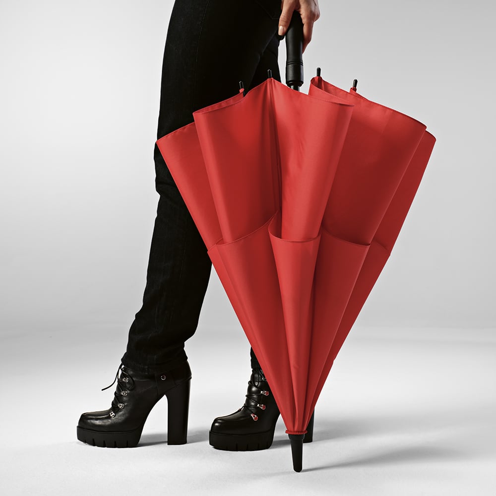 A red storm-proof umbrella with automatic opening, held by a person wearing black high-heeled boots.