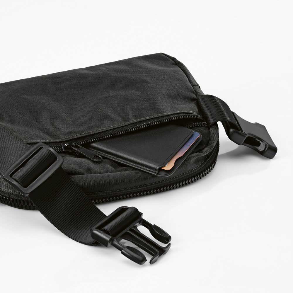A black waist bag with two pockets and an adjustable strap, featuring a card tucked inside one pocket.