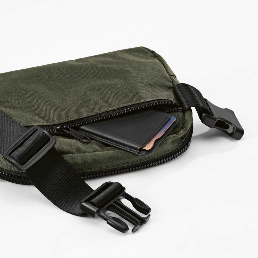 A green waist bag with a black adjustable strap and a zippered pocket containing a cardholder. Includes a logo.