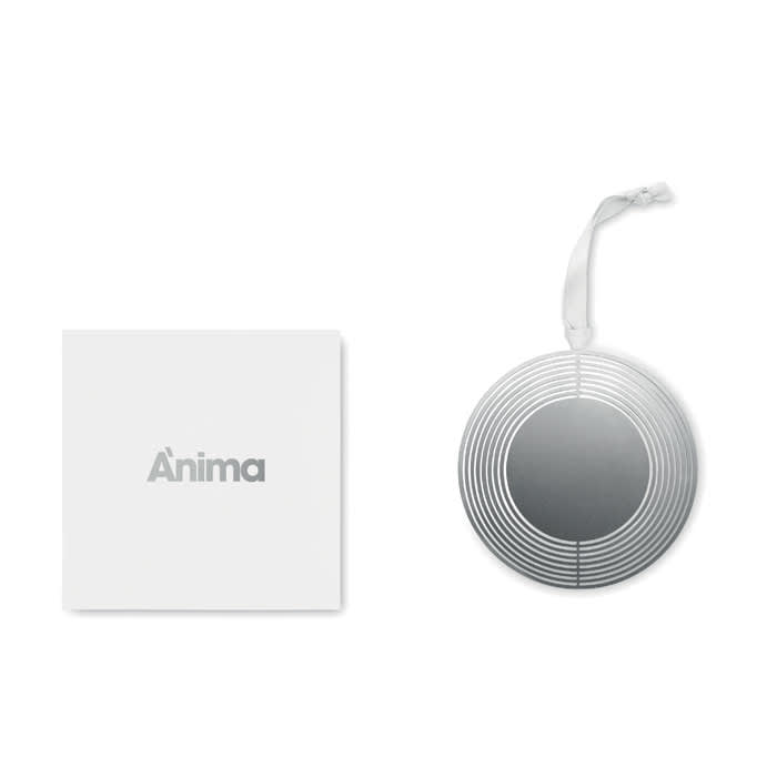 A round silver decorative item with a striped design, placed beside a white box featuring branding.