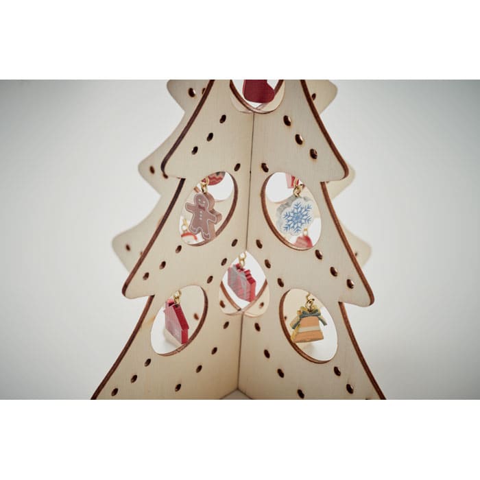 A decorative wooden Christmas tree featuring cut-out holes, adorned with small festive ornaments in various shapes.