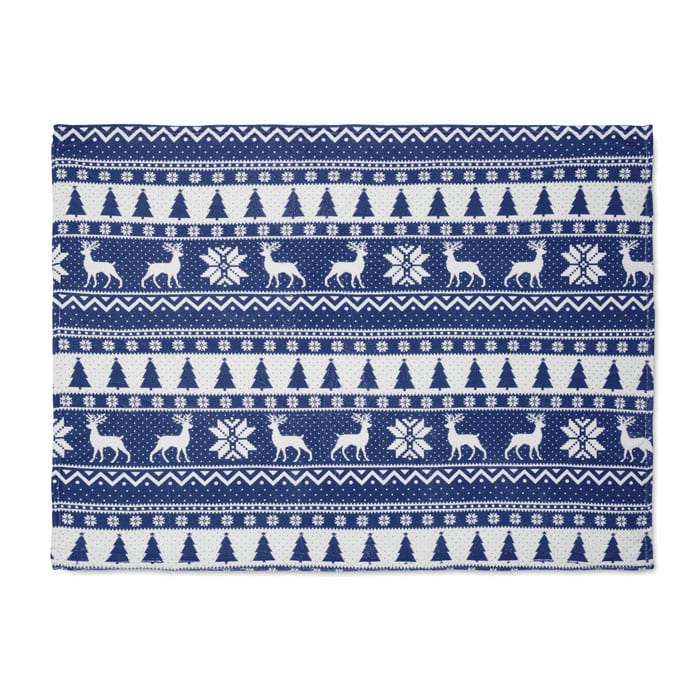 A decorative rug featuring a navy blue and white pattern with reindeer, trees, and snowflakes.