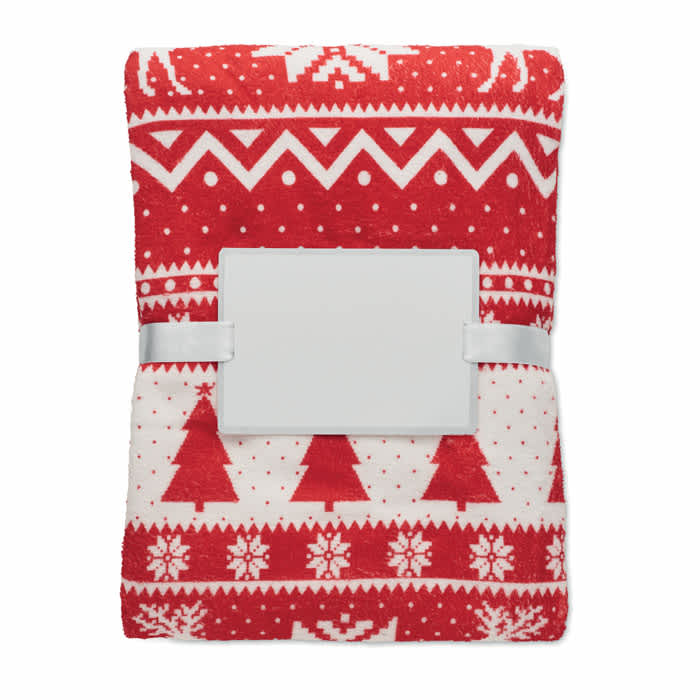 A red and white blanket featuring a festive pattern with trees and snowflakes, secured with a white band.