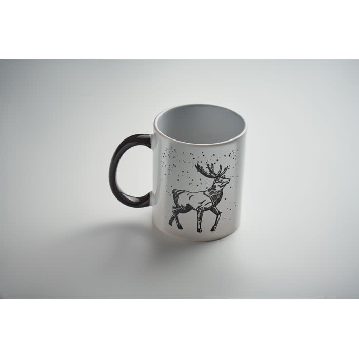 A white mug with a black handle featuring a deer illustration and a speckled background.