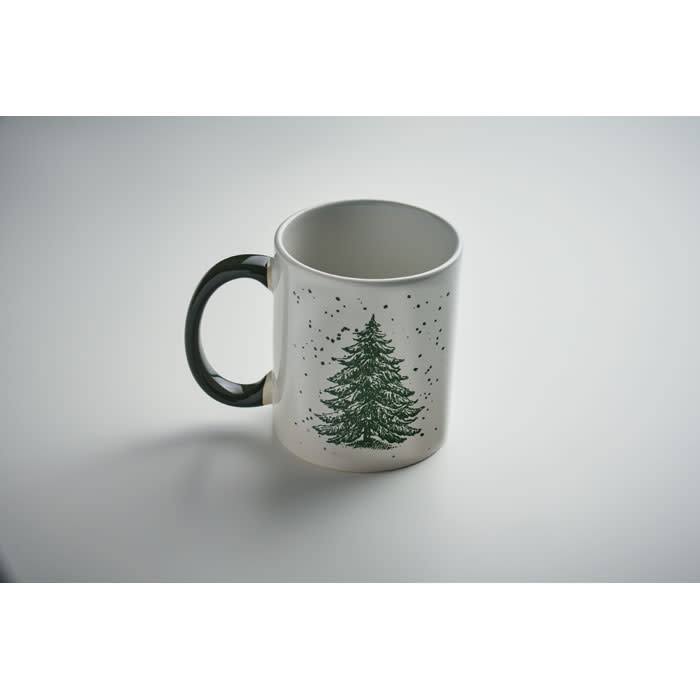 A ceramic mug featuring a green tree design, with a black handle and a white background.