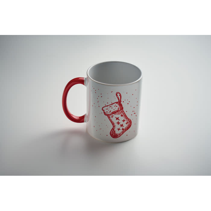 A white mug with a red handle featuring a red stocking design and scattered red stars.