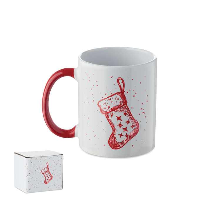 A drink mug with a white ceramic body, red handle, and decorated with a red stocking design. Includes a box.