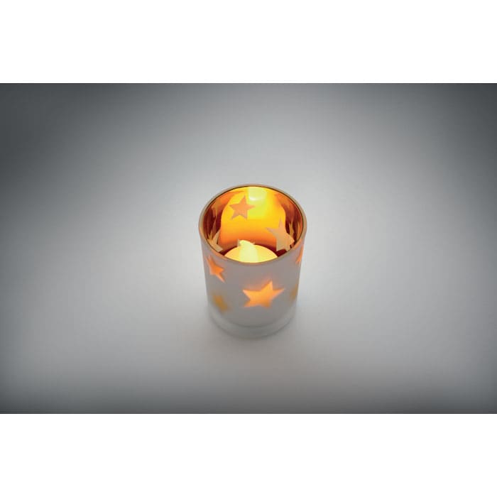 A candle holder with a silver and gold finish, featuring star cutouts that illuminate when a candle is placed inside.