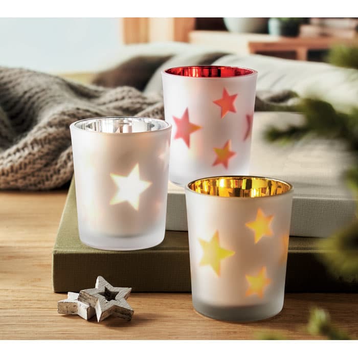 A set of three decorative candle holders in frosted glass, featuring star cut-outs in white, gold, and red colours.