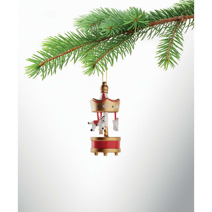 A gold and red carousel ornament hanging from a pine branch, featuring small figurines attached.
