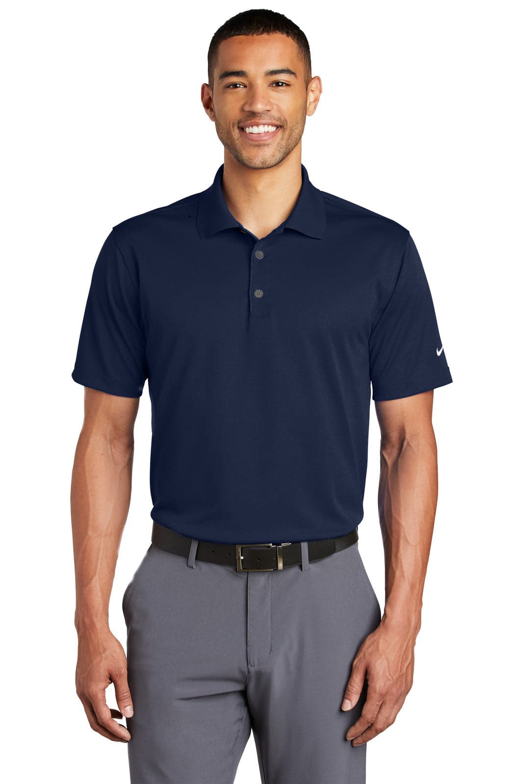 A navy blue Nike Tech Basic Dri-FIT polo shirt with a logo, modelled by a man wearing grey trousers.