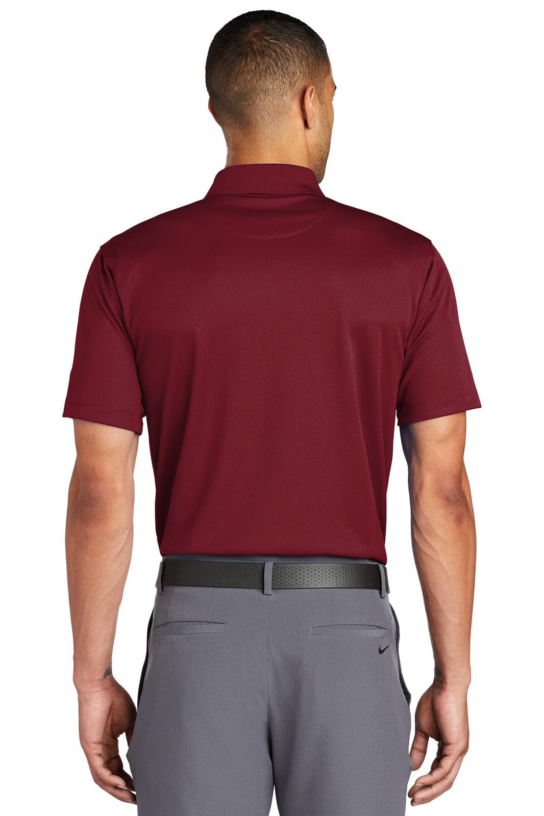 A maroon Nike Tech Basic Dri-FIT Polo shirt viewed from the back, featuring a logo and paired with grey trousers.
