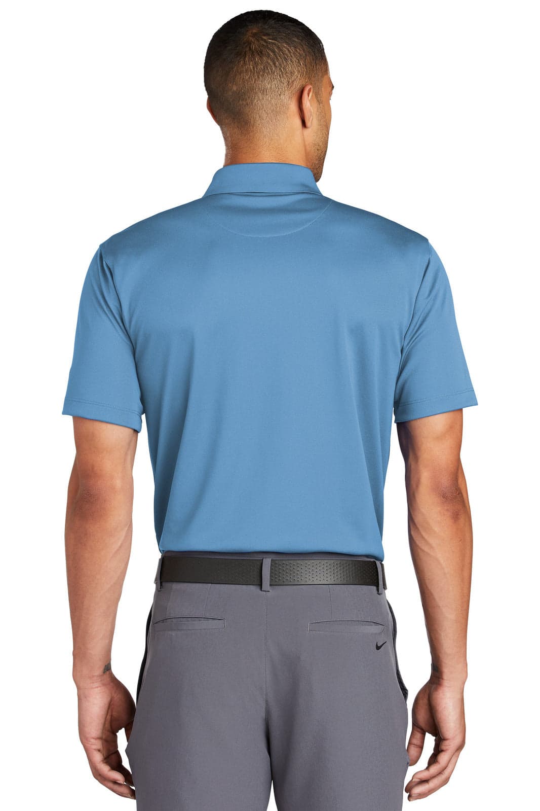 A back view of a blue Nike Tech Basic Dri-FIT polo shirt, worn with grey trousers. The shirt has a logo.