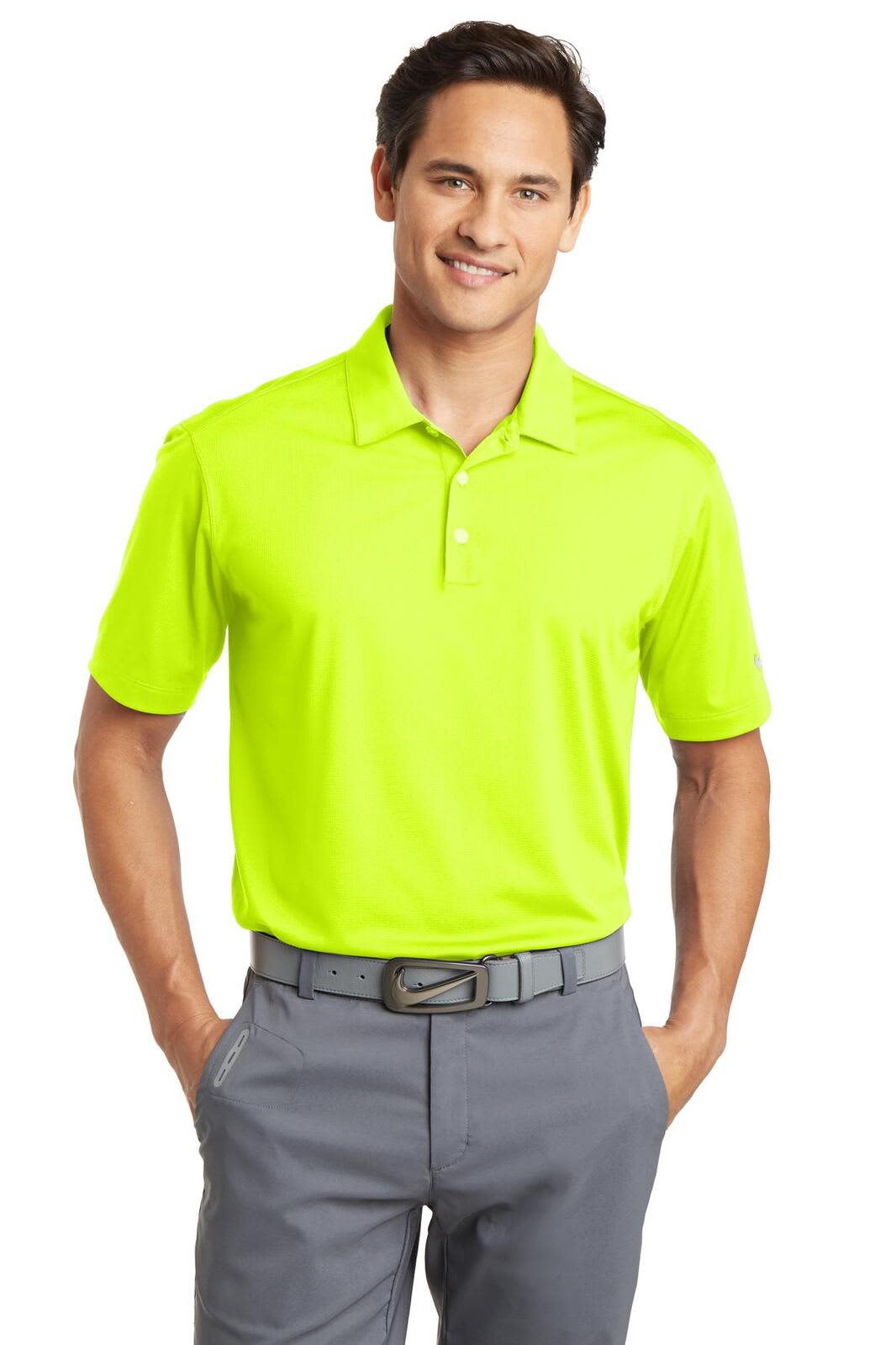 A bright lime green Nike Dri-FIT vertical mesh polo shirt on a model, paired with grey trousers. The shirt features a logo.