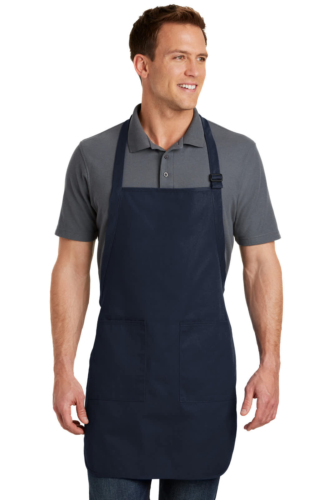 A man wearing a navy full-length apron with pockets, standing and smiling. The apron features a logo.