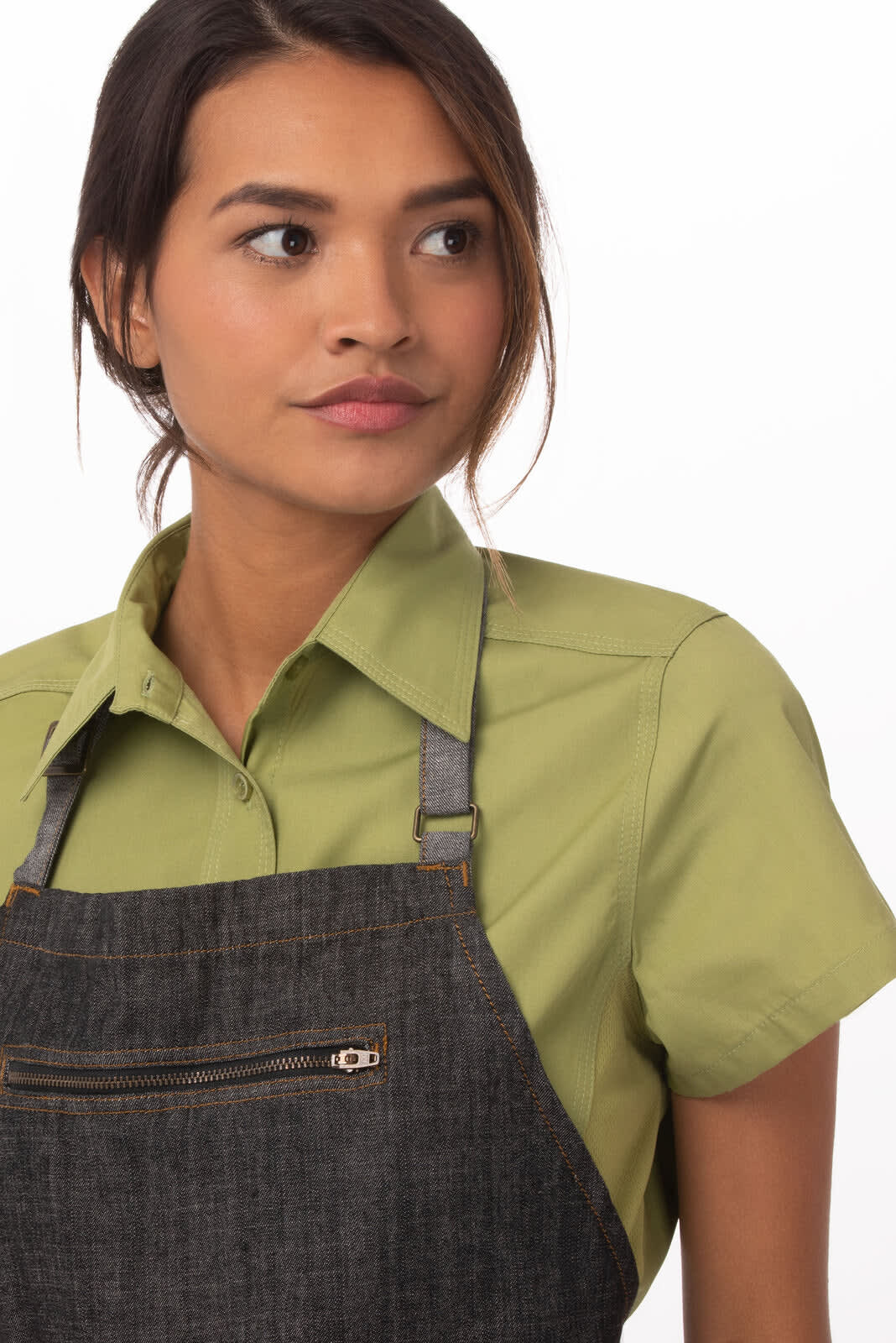 A dark denim bib apron with a front zipper pocket, modelled by a woman wearing a light green shirt.