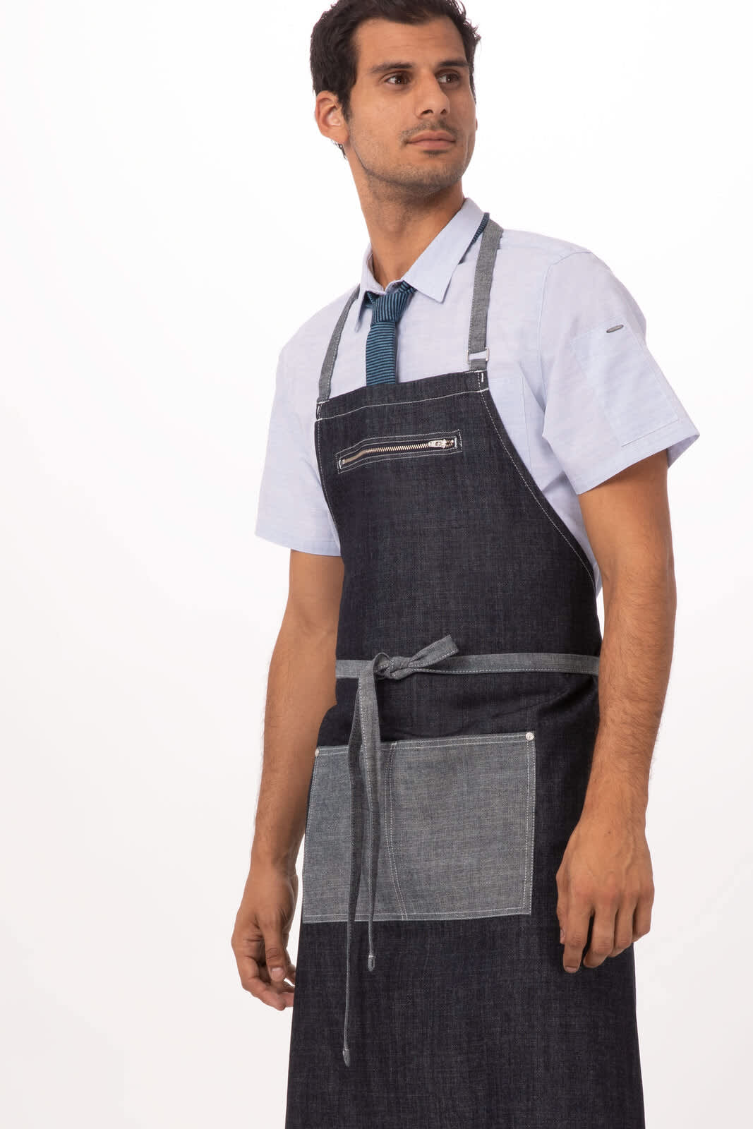 A dark denim bib apron featuring a front pocket, adjustable neck straps, and a stylish design. It has branding visible.