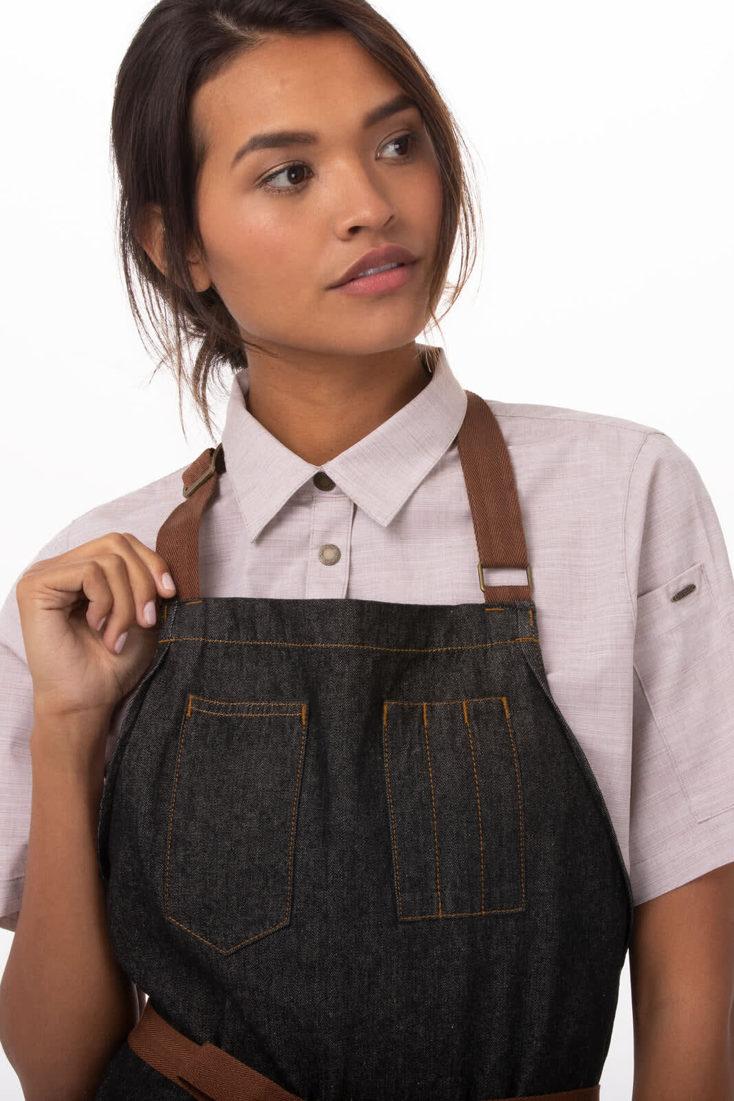 A dark denim apron with brown leather straps, featuring two front pockets.