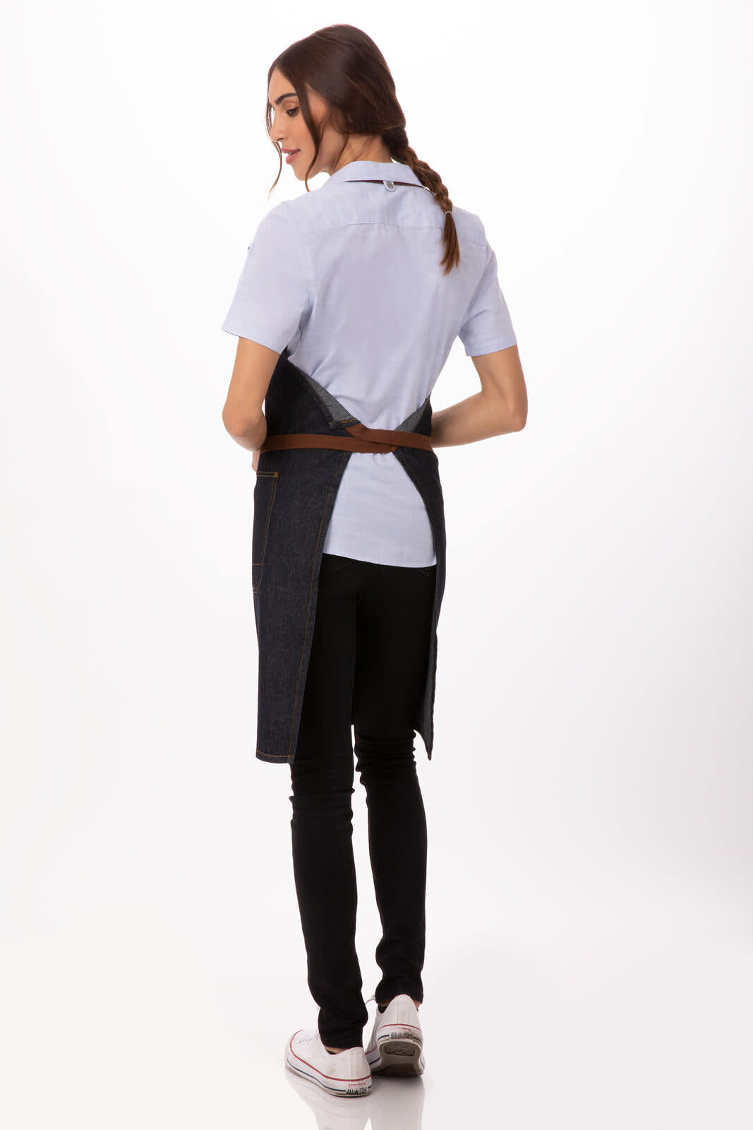 A woman wearing a dark blue Memphis Bib Apron over a light blue shirt, displaying a sleek design and fitted style.