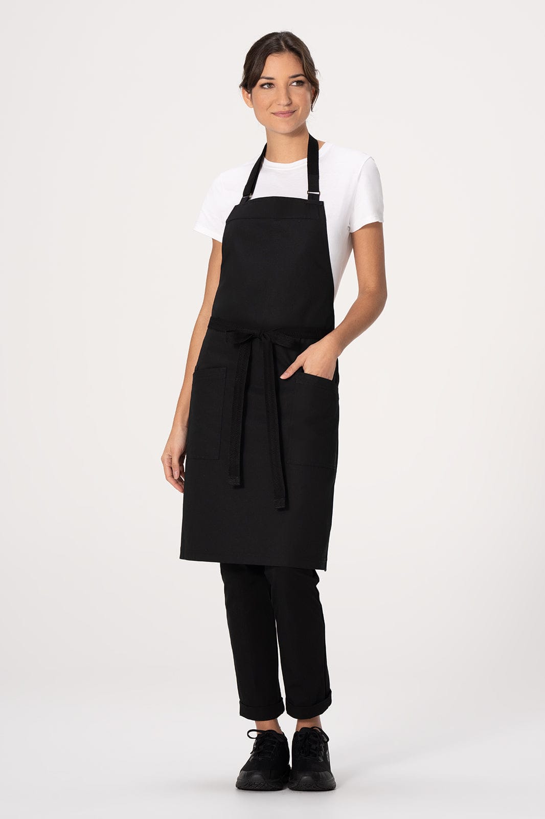 A black bib apron worn over a white t-shirt, featuring a front pocket and a waist tie.