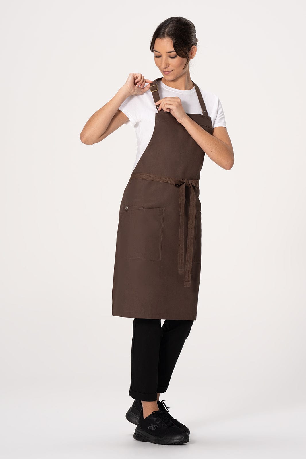 A brown Lockharte bib apron worn by a model, featuring a tie waist and a logo on the side.