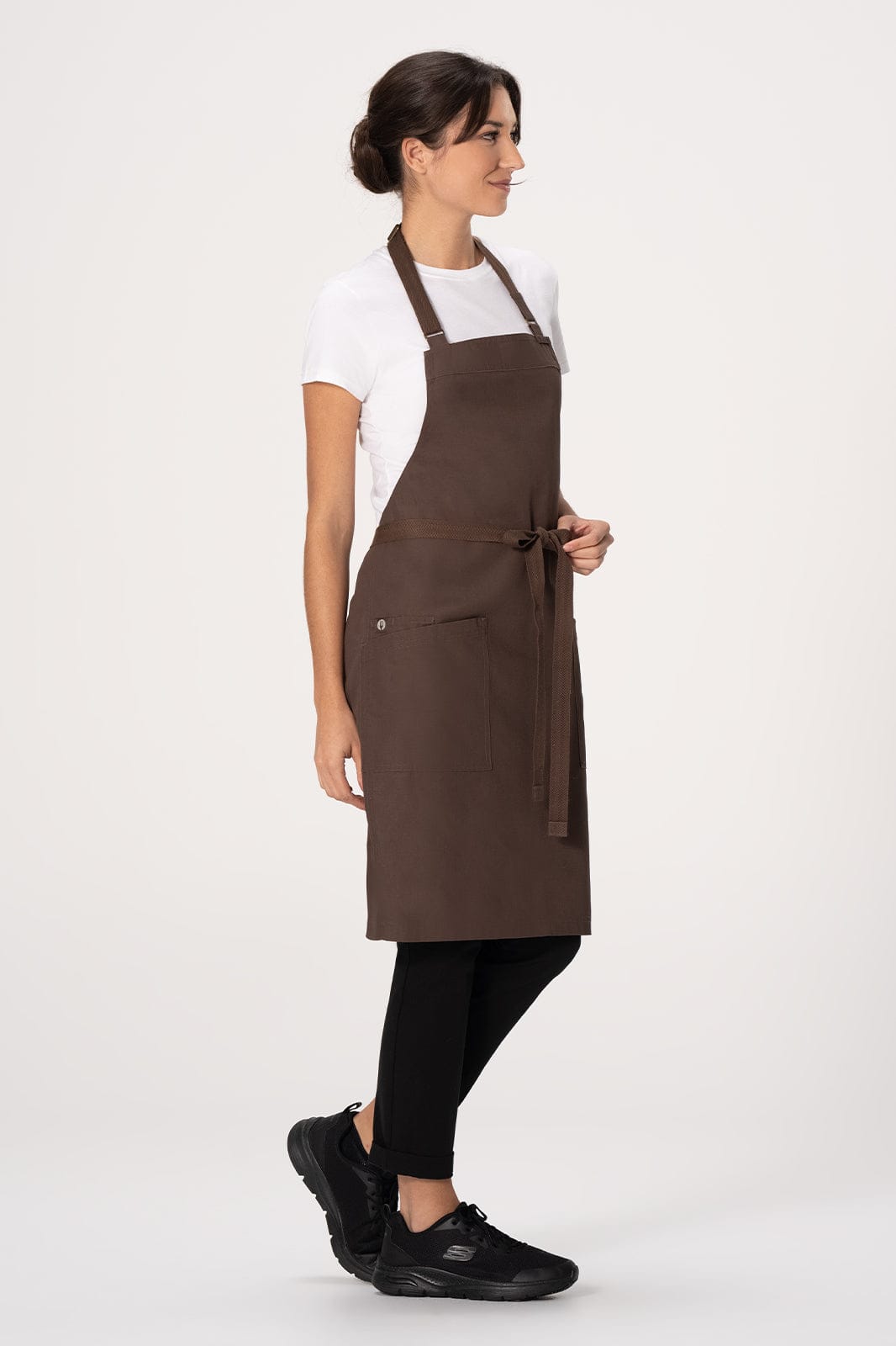 A brown bib apron is displayed on a model, paired with a white t-shirt and black pants, featuring a logo.