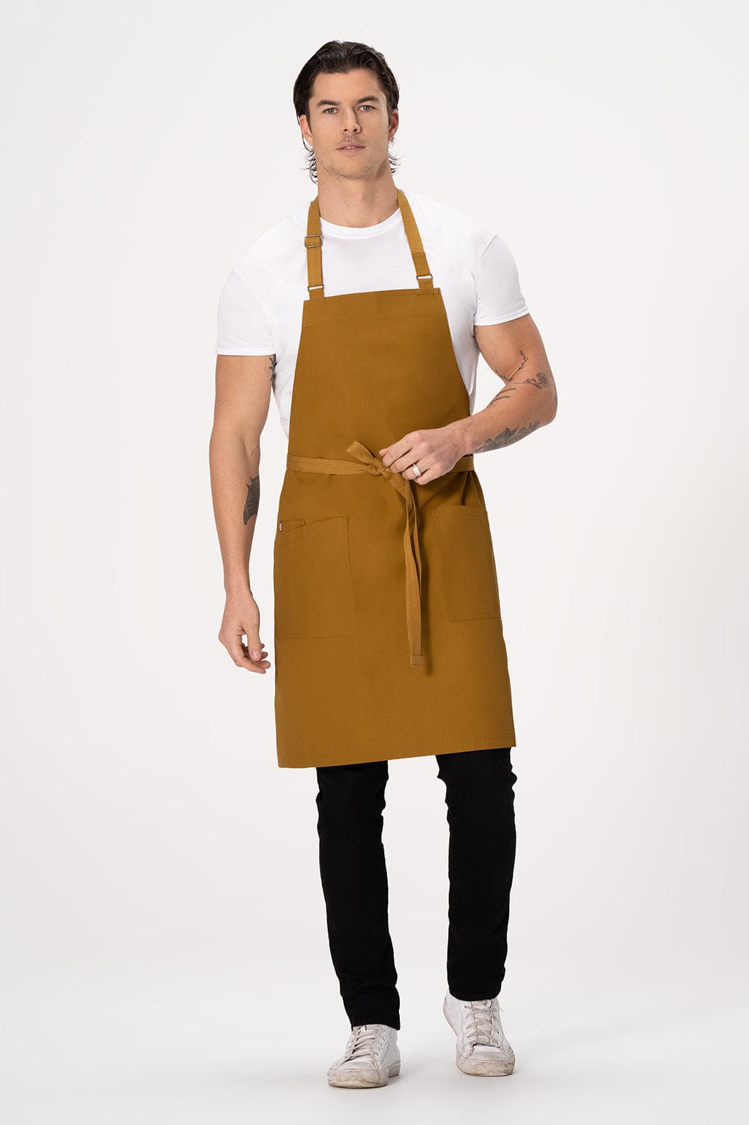 A man wearing a mustard yellow Lockharte bib apron over a white t-shirt and black pants, with a logo present.