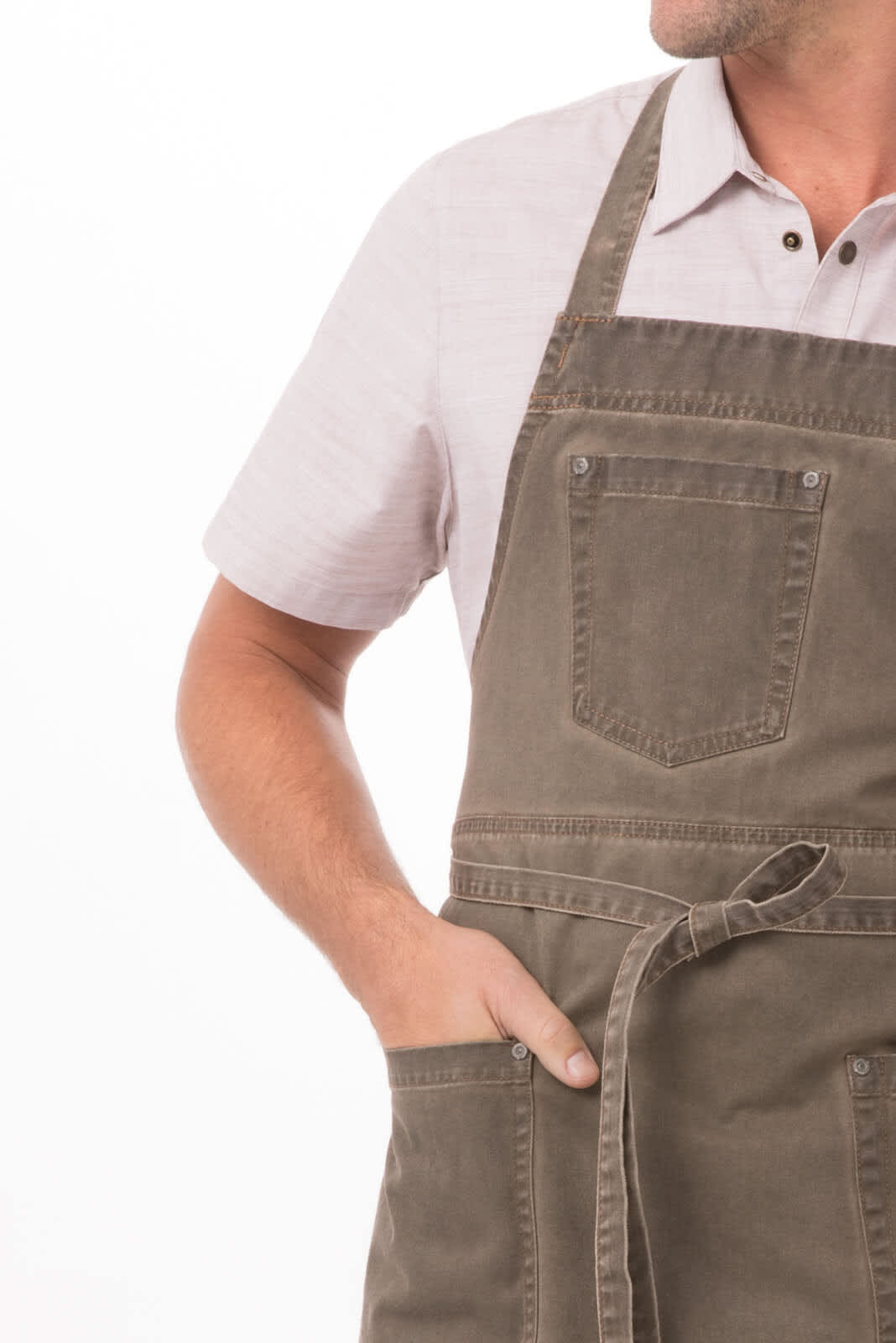 A brown Dorset bib apron with a pocket and ties, displayed on a person wearing a light-coloured shirt.