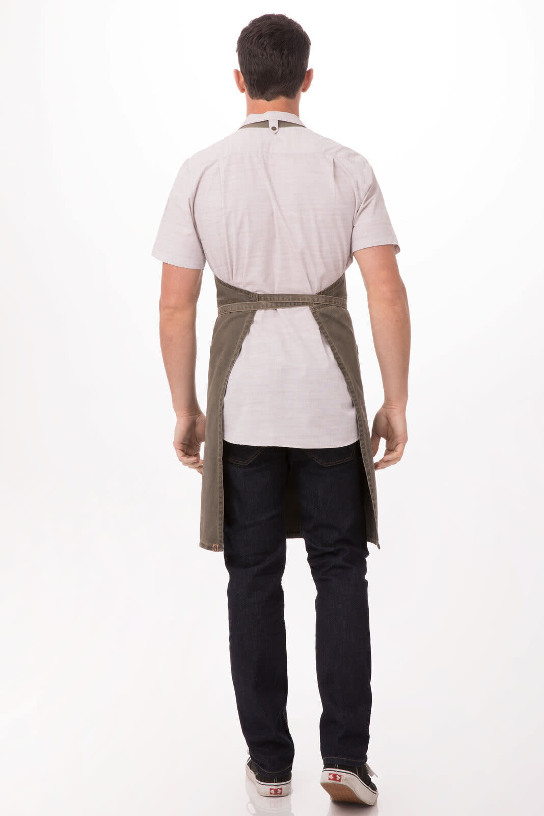 A person wearing a green Dorset Bib Apron over a light-coloured shirt and dark jeans, viewed from the back.