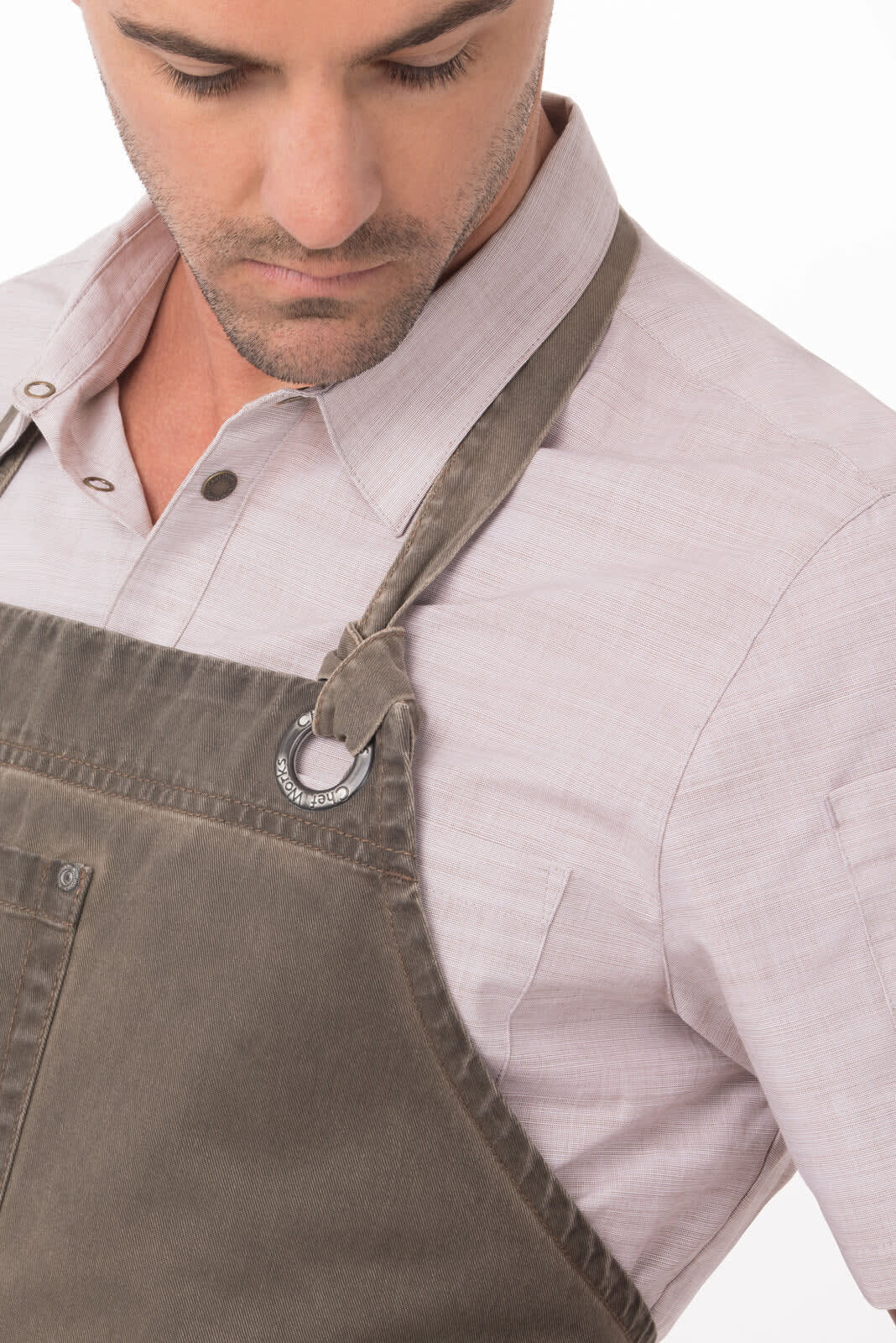 A grey Dorset Bib Apron featuring adjustable straps and a metal fastening, showcased on a model wearing a light-coloured shirt.