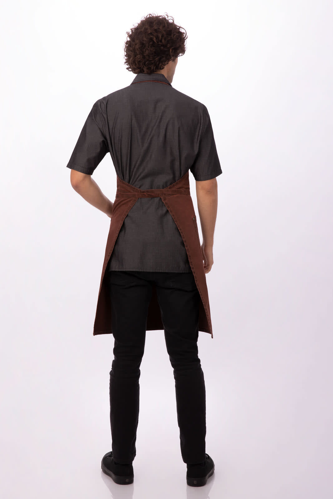 A brown Dorset Bib Apron worn over a black shirt, viewed from the back, featuring a logo.