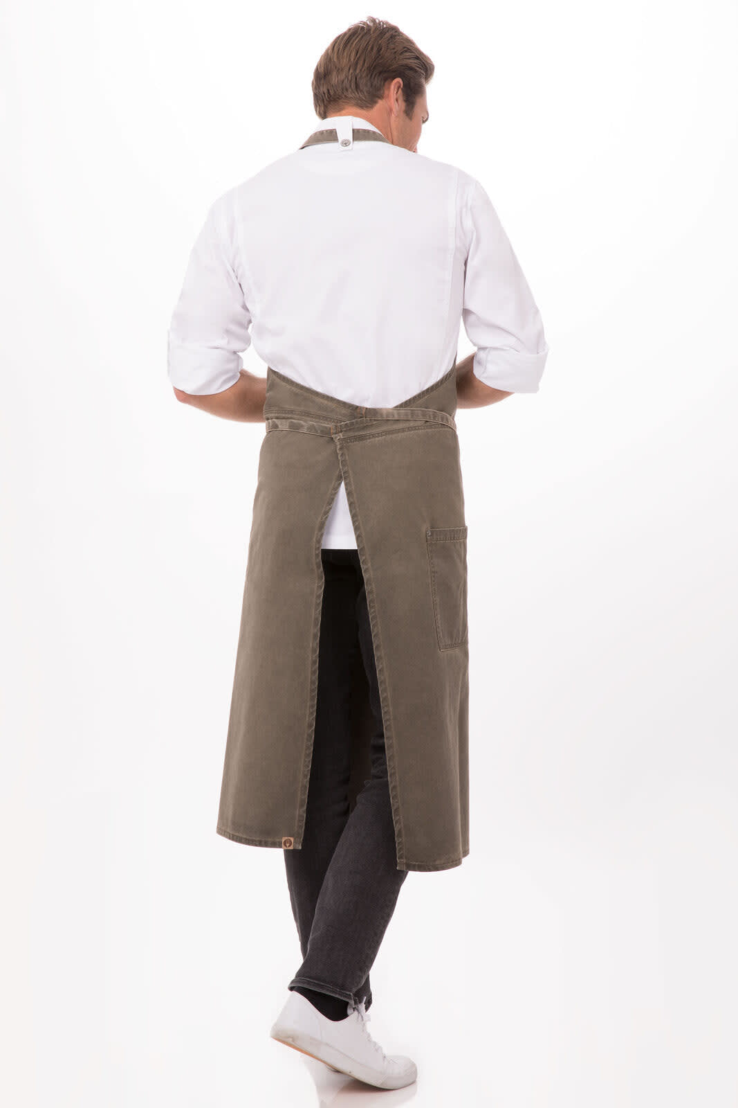 A khaki Dorset Chefs Bib Apron worn backwards by a model, featuring a simple design and a brand logo.