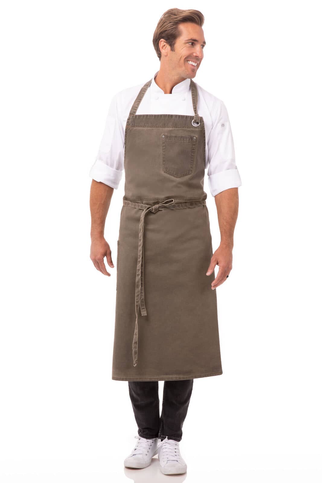 A man in a dark olive green bib apron, featuring a front pocket and a tied waist. The apron has a logo.