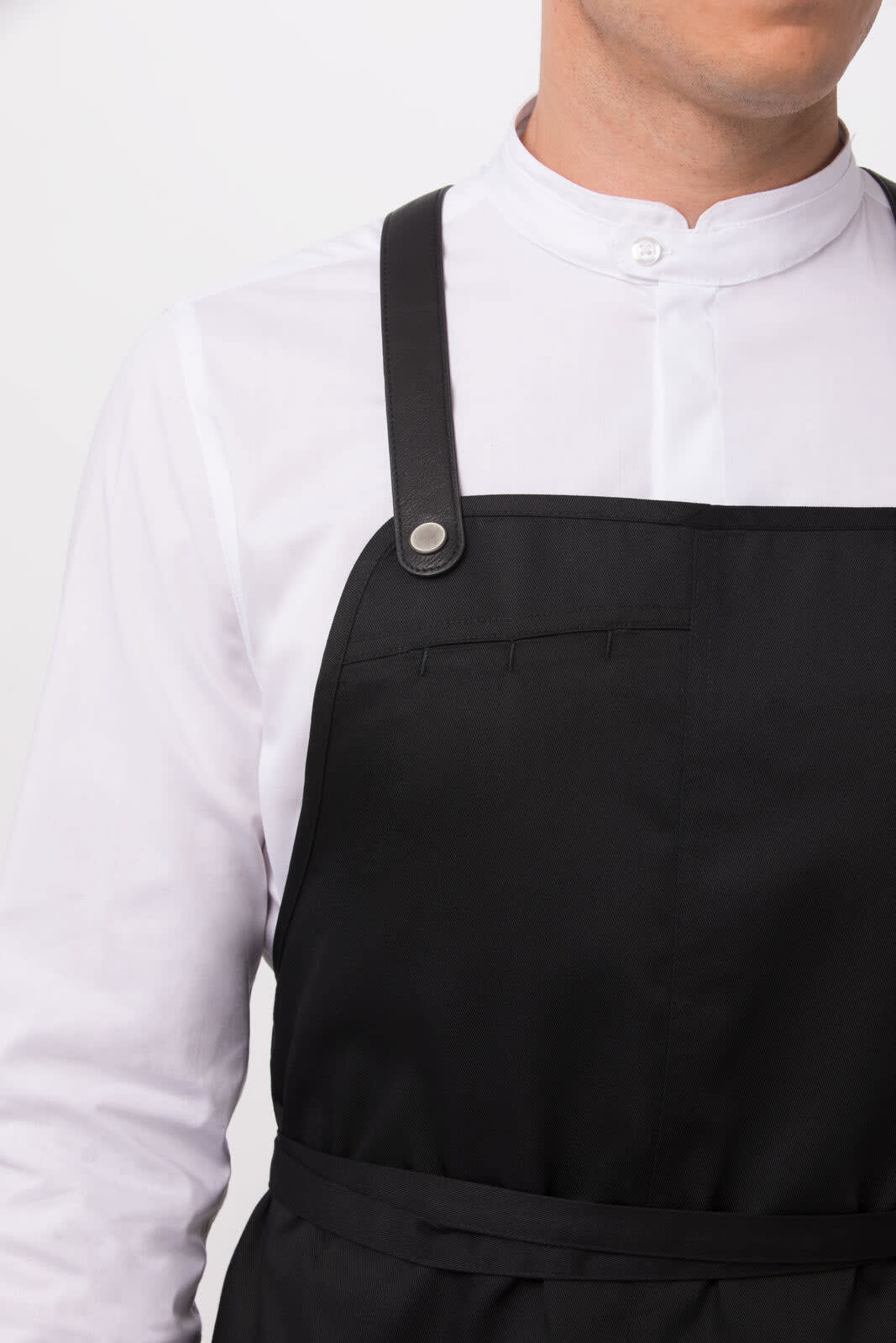 A black Largo Bib Apron worn over a white collared shirt, featuring leather straps and a clean design.