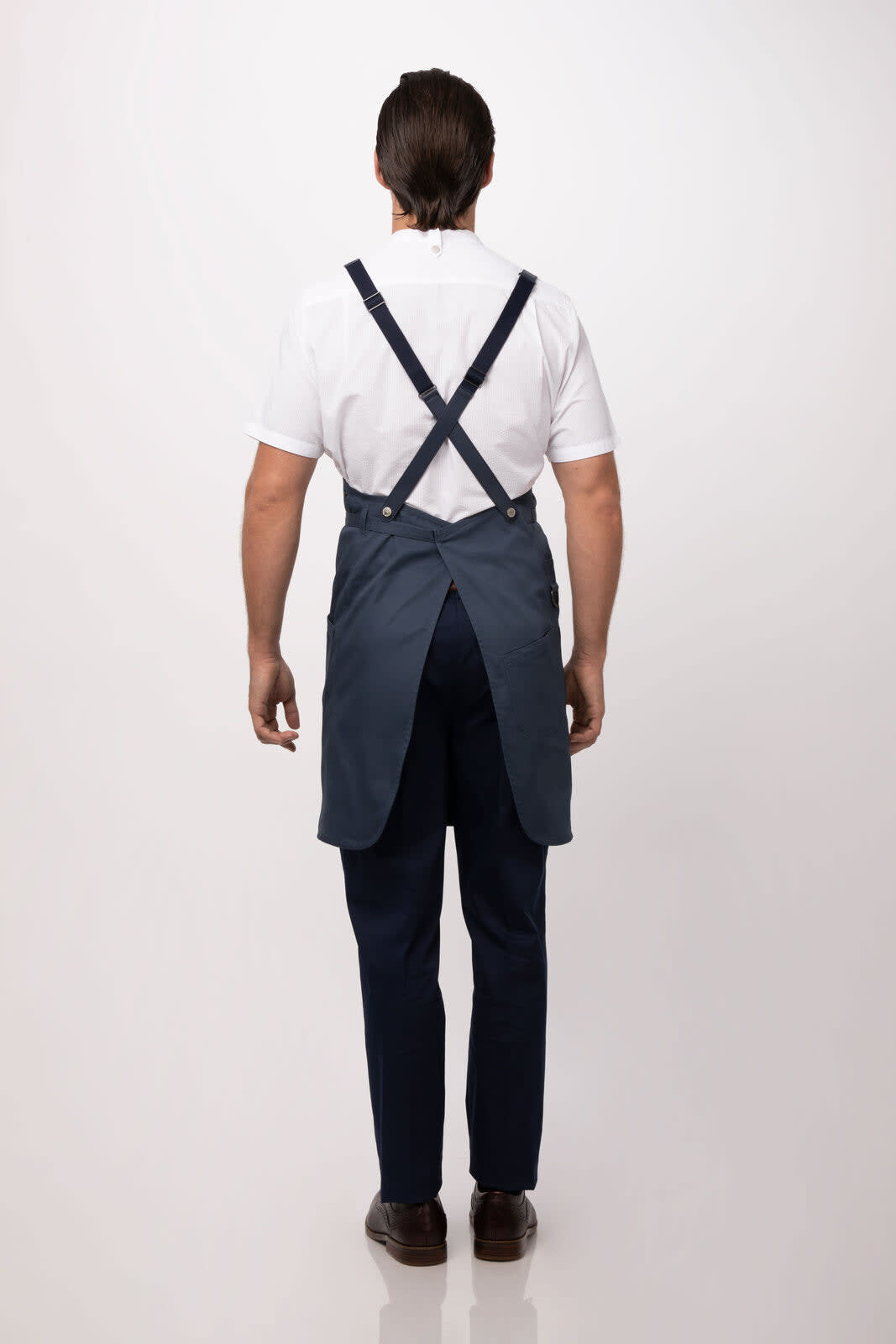 A navy blue bib apron with adjustable straps, worn by a person facing away, displaying a simple design and a logo.